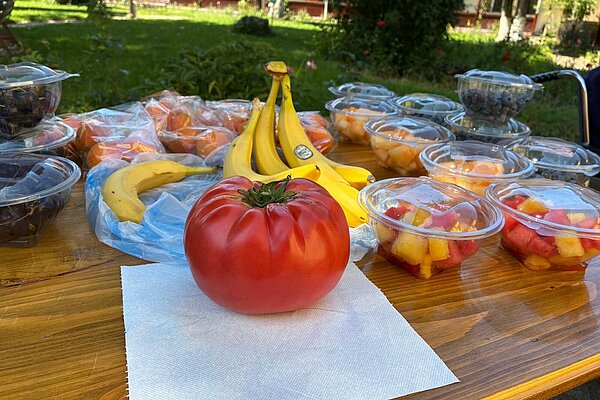 Frisches Obst auf dem Tisch: Bananen, Mandarinen, Obstbecher