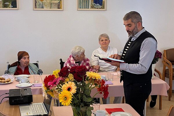 Blumen und Gebäck auf dem Tisch, ein Redner mit Buch