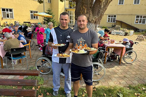 Zwei Männer aus dem Team zeigen die ersten vollen Teller