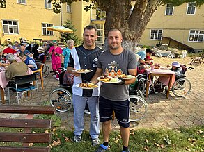 Zwei Männer aus dem Team mit den ersten Tellern vom Grill