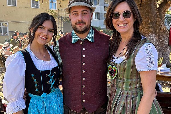 Drei junge Leute in Dirndl und Lederhose unter der Platane