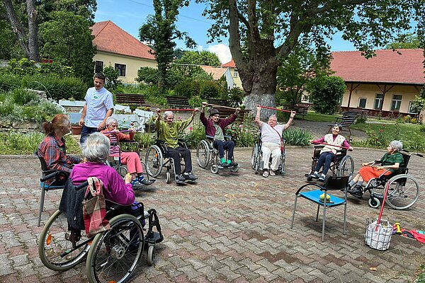 Gymnastik mit Gummibändern im Halbkreis unter der Platane