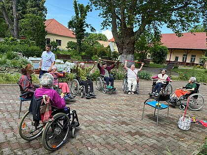 Gymnastik mit Gummibändern im Halbkreis unter der Platane