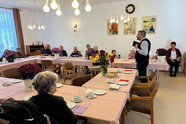 Ein Redner spricht zu den Bewohnern an den festlichen Tischen